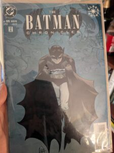 The cover of an issue of The Batman Chronicles, Winter 98. The background is dark blue-green, Batman is clutching his cape in each hand and smiling, facing the reader straight on. The text of the title is in white. It cost CAD4.25