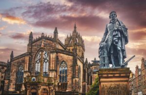 The statue of Adam Smith in Edinburgh in front of a dramatic purplish sky. Photo by K Mitch Hodge on Unsplash.